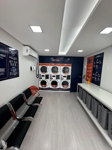 Interior da Acqua Nova Suíça: seis máquinas, bancada com cestos, assentos e ar-condicionado